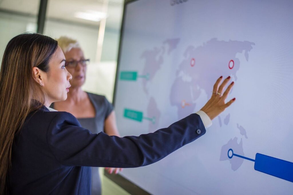 A business woman and a peer discuss opportunities while studying a global map.